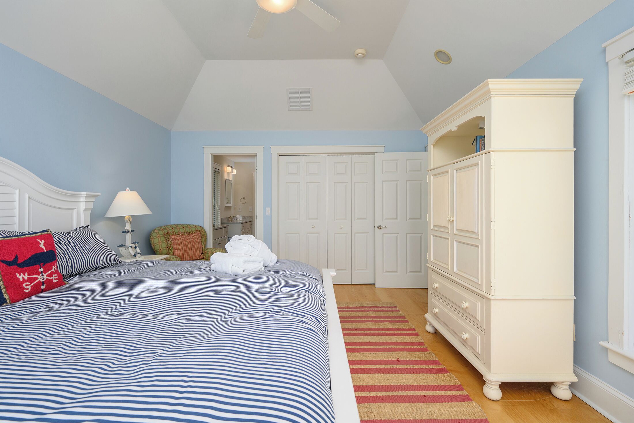 A bedroom with a bed, a dresser, a mirror, and a door.