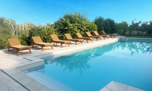A swimming pool with lounge chairs and a clear sky.