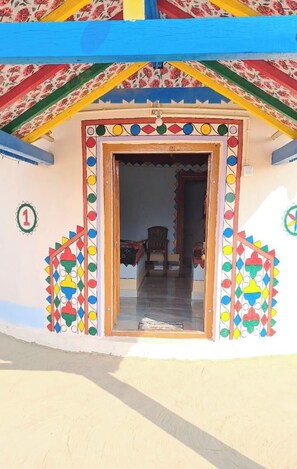 A colorful building entrance with a door, a number '1' sign, and a patterned wall. - Rann taara stay (Bhuj)