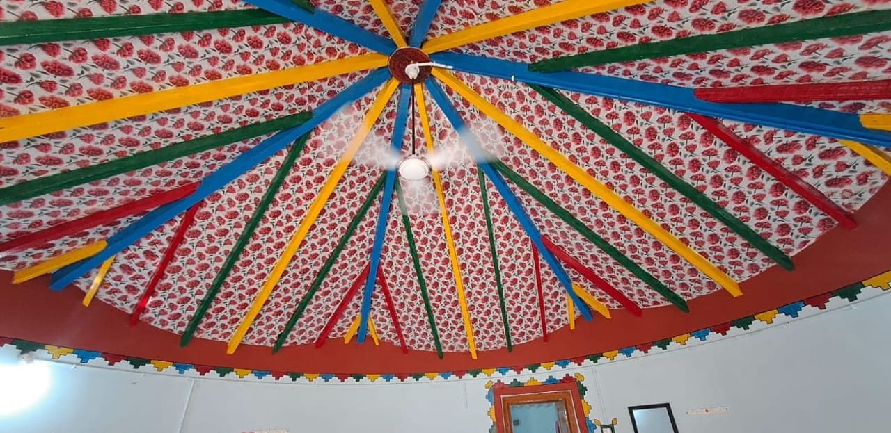 A room with a colorful, patterned ceiling and a door with a mirror.