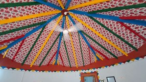 A room with a colorful, patterned ceiling and a door with a mirror. - Rann taara stay (Bhuj)