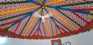 A room with a colorful, patterned ceiling and a door with a mirror. - Rann taara stay (Bhuj)