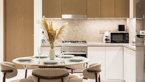 Een moderne keuken met een ronde eettafel, witte kastjes en een ingebouwde magnetron.