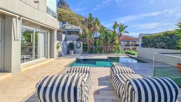 A modern pool area with striped cushions, a clear pool, and a mountain backdrop. - Villa Disdant , Fresnaye , Cape Town (Cape Town)