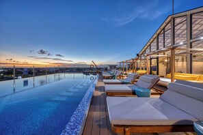 A rooftop infinity pool with lounge chairs and a glass-enclosed structure. - XO Canggu Adults Only (Canggu)