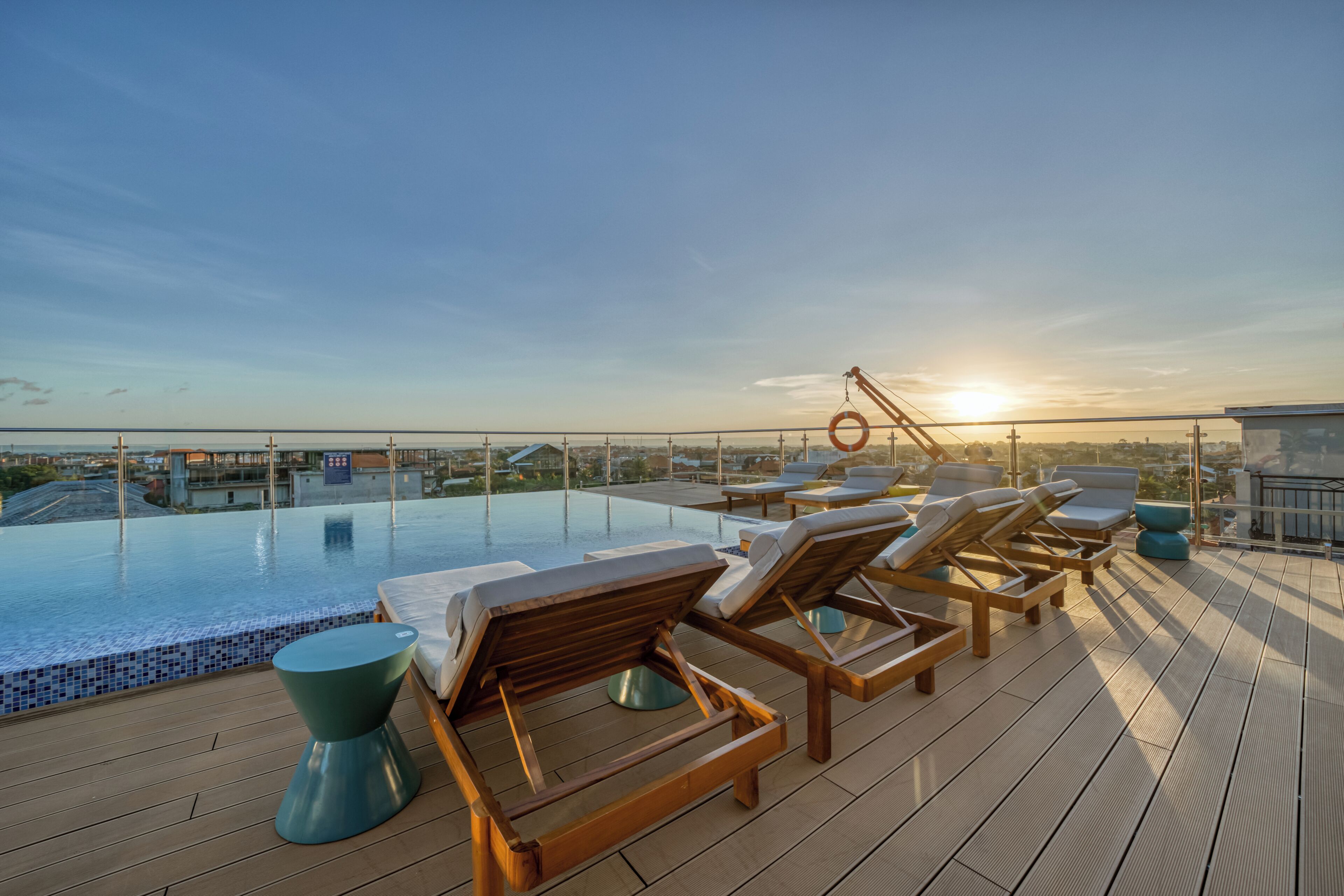 Un espace piscine aménagé sur le toit, avec des chaises longues et une vue sur le coucher du soleil.