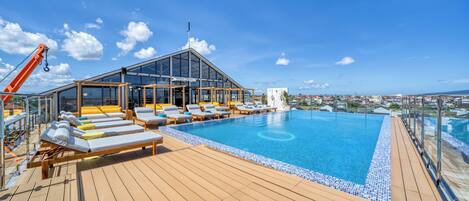 A poolside area with sun loungers, a glass-enclosed structure, and a clear view of the ocean.