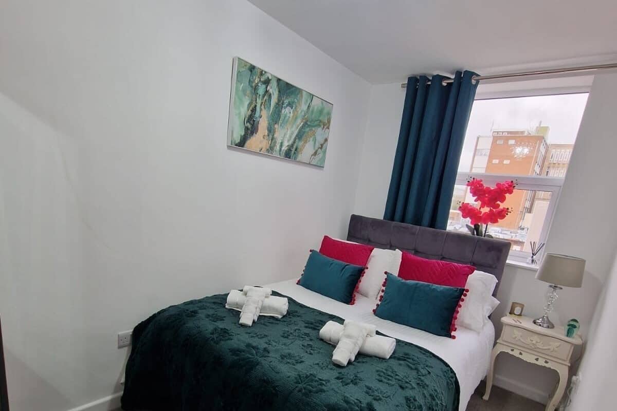 Une chambre à coucher avec un lit, une table de chevet, une chaise et une fenêtre avec des rideaux.