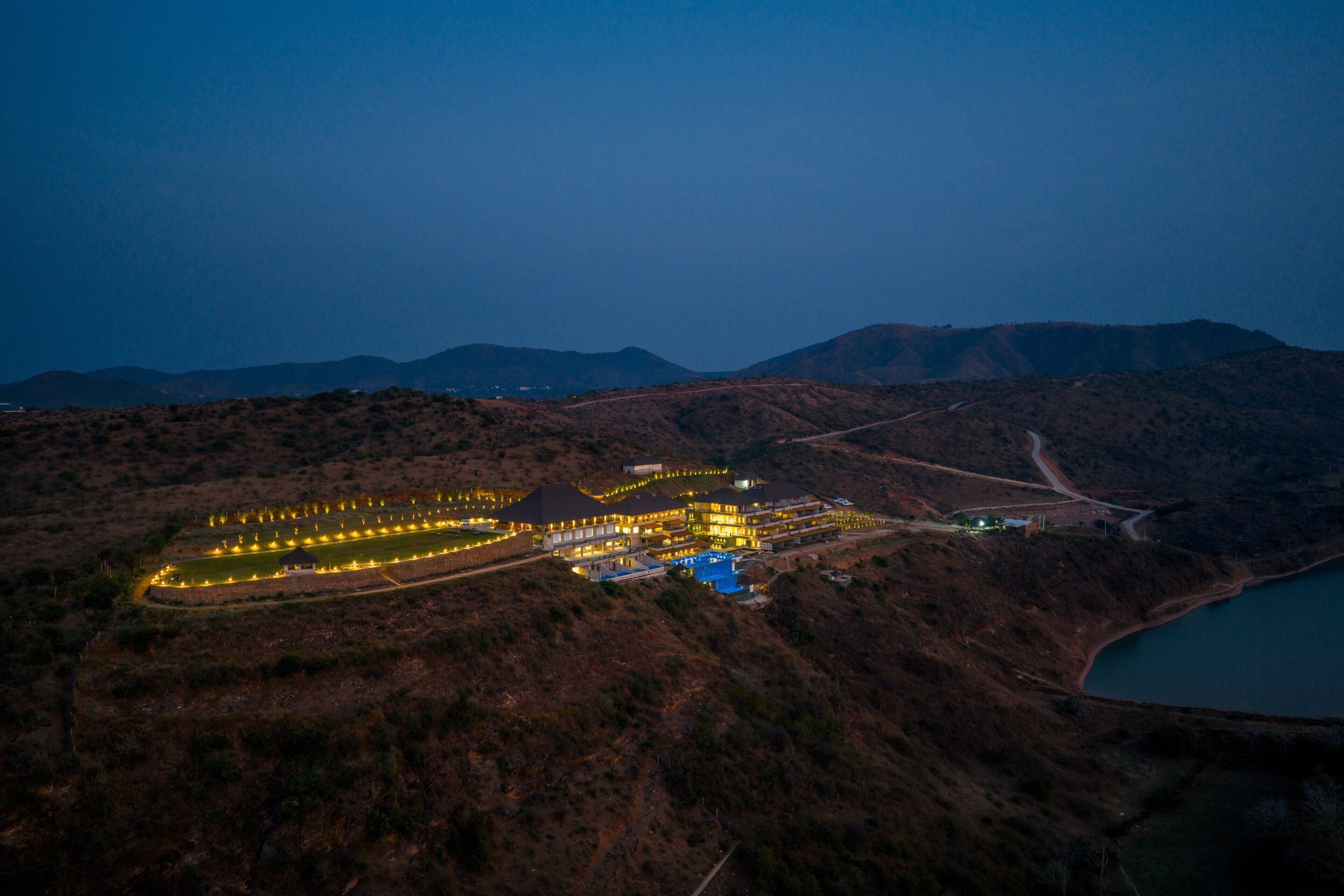 An aerial view of a resort with multiple buildings, a swimming pool, and a lake.