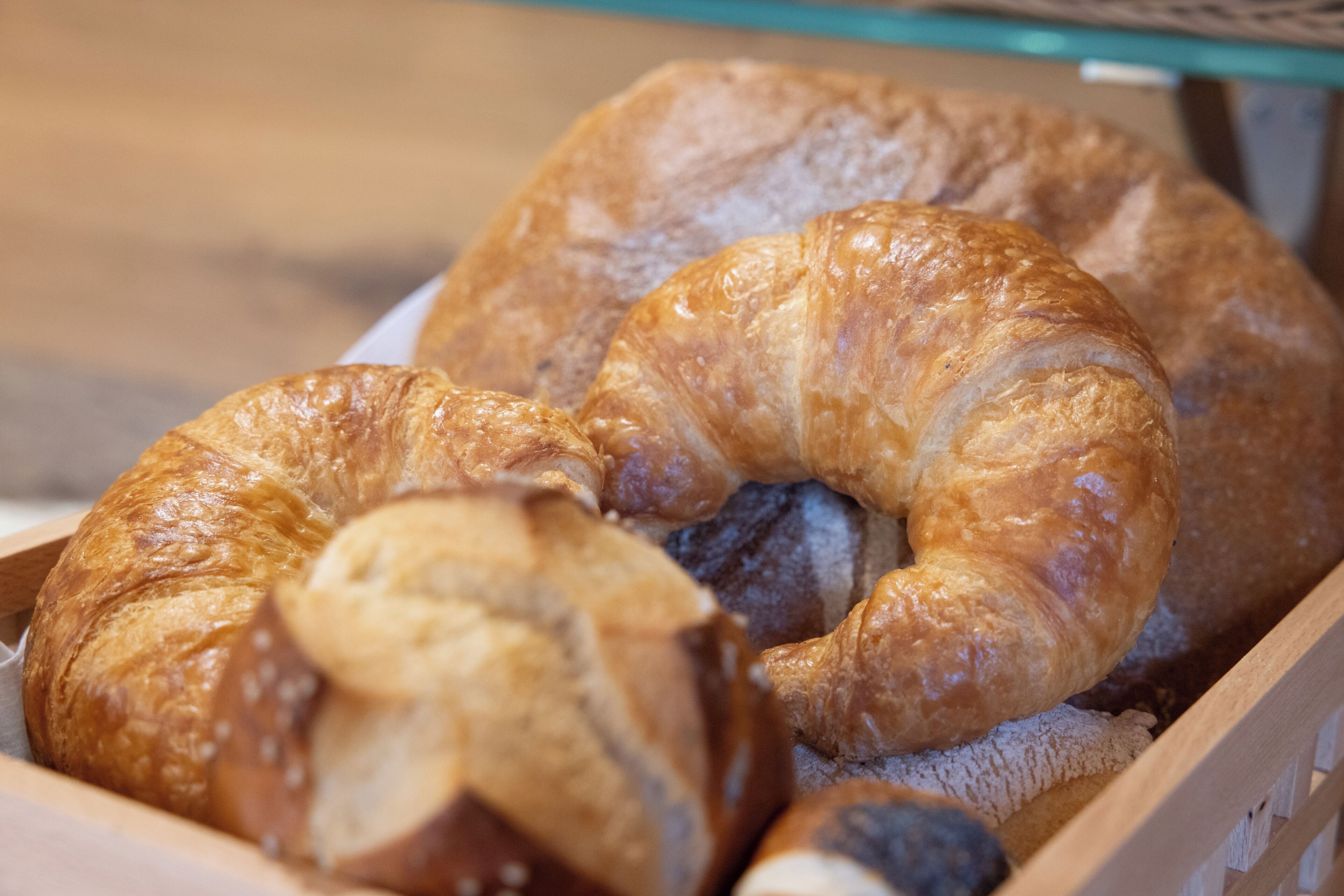 A wooden box containing several croissants.