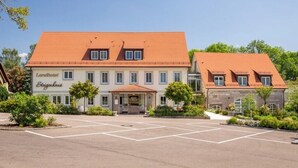 A two-story hotel with a red-tiled roof, a central entrance, and a parking lot. - Landhotel Steigenhaus (Untermünkheim)