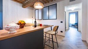 A kitchen with a wooden island, a chair, and a dining table.