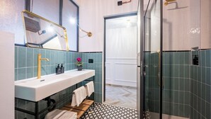 A bathroom with a white sink, gold faucet, and a shower with a glass door.