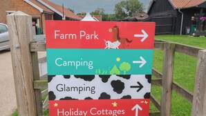 A directional sign with arrows pointing to Farm Park, Camping, Glamping, and Holiday Cottages. - Molly (Woodbridge)