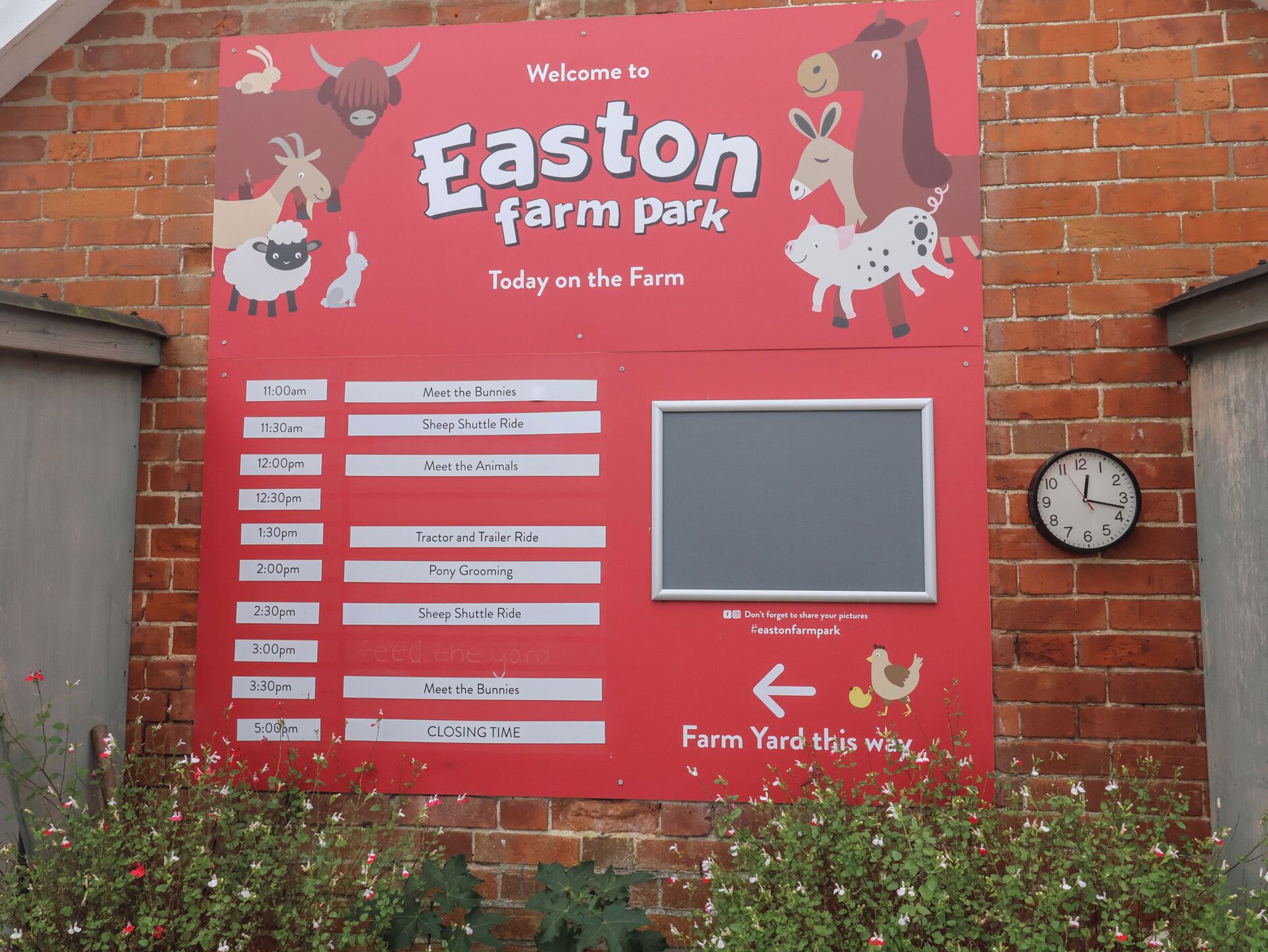 Un panneau rouge indiquant le parc Easton Farm, avec un programme des activités.