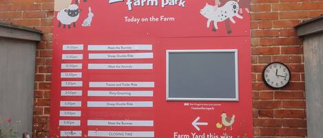 Un panneau rouge indiquant le parc Easton Farm, avec un programme des activités.