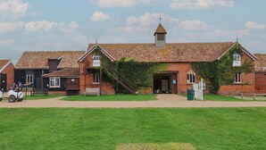 A traditional brick building with a tiled roof, a small tower, and a gravel driveway. - Molly (Woodbridge)