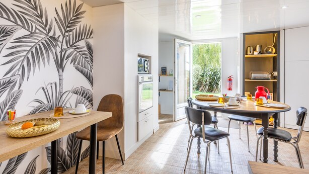 Una cocina moderna con comedor, que cuenta con un ventanal grande, un refrigerador y una cafetera.