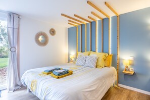 A bedroom with a bed, bedside lamps, a window with curtains, and a view of the outdoors.