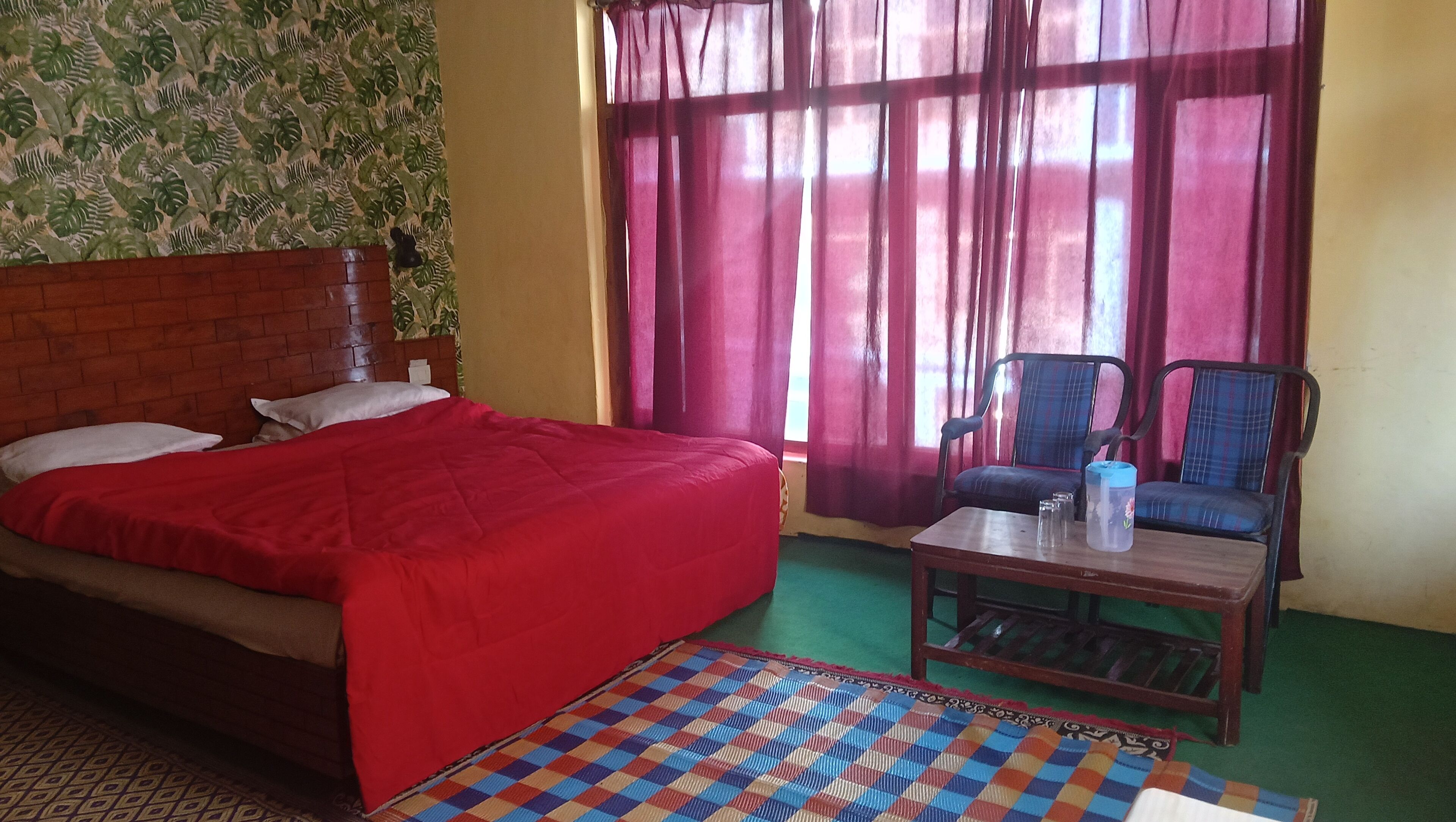 Une pièce comprenant un lit, une chaise, une table et une fenêtre avec des rideaux.