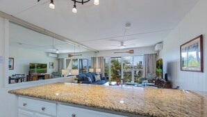 A spacious kitchen with a granite countertop, white cabinetry, and a large island. - New Listing! Akahi C613 – Ocean View Top Floor Condo, Newly Updated, Sleeps 4 (Kihei)