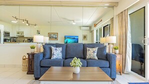 A living room with a sofa, coffee table, and a view of the kitchen and dining area. - New Listing! Akahi C613 – Ocean View Top Floor Condo, Newly Updated, Sleeps 4 (Kihei)