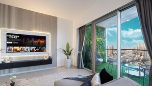 A modern living room with a large TV displaying 'Stranger Things' and a balcony with a city view.