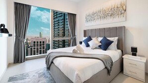 A modern bedroom with a large bed, a nightstand, and a view of a cityscape through large windows.