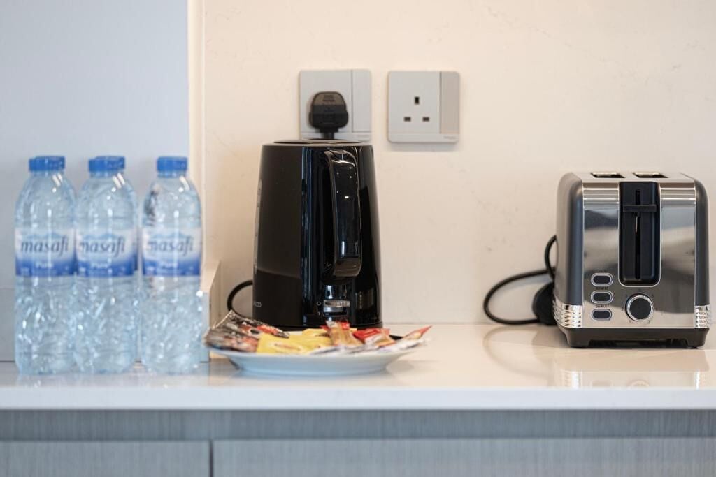 A kitchen counter with a coffee maker, a toaster, and three water bottles.