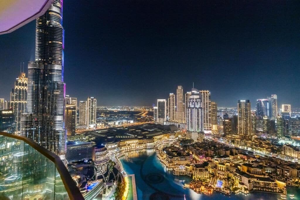 Une vue nocturne d’une ville, avec des gratte-ciel illuminés et une tour imposante.