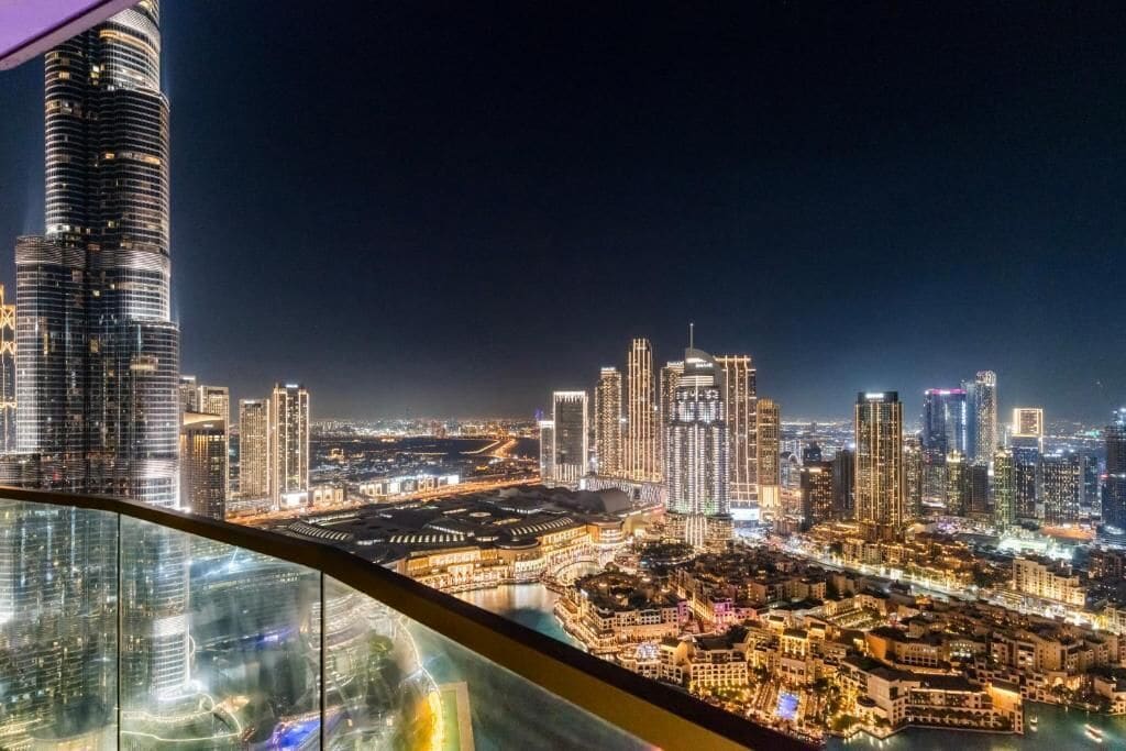 A nighttime cityscape with a prominent skyscraper and a view of the urban area below.