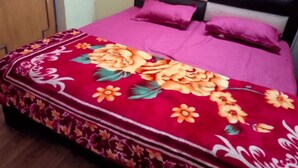 A bed with a floral bedspread and two pillows. - Hotel Raj Ratan (Kanpur)