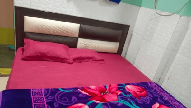 A bed with a red bedspread and a floral-patterned blanket. - Hotel Raj Ratan (Kanpur)