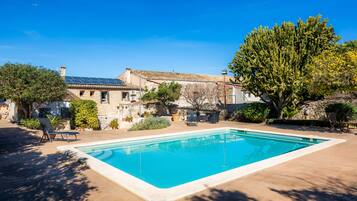 Una piscina con una casa de piedra al fondo.