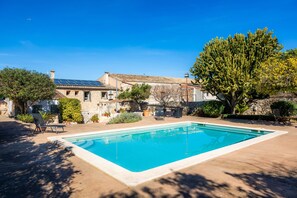 A swimming pool with a stone house in the background.