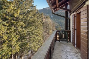A wooden deck with a view of a forested mountain area.