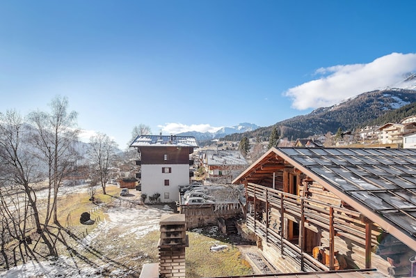 Un village de montagne aux maisons traditionnelles en bois, sous un ciel dégagé, et dont le sol est recouvert de neige.