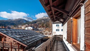 Un balcón de madera con vistas a una montaña y edificios.