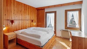 Un dormitorio con paneles de madera, una cama, mesitas de noche y una ventana con vistas.