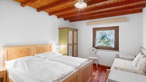 A bedroom with a wooden bed, a small chair, a cabinet, and a window with a view. - Room with Mountain View and Wi-Fi (Vigo di Fassa)