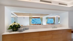 Une salle de bain moderne avec un grand miroir, des meubles en bois, un lavabo et une plante en pot.