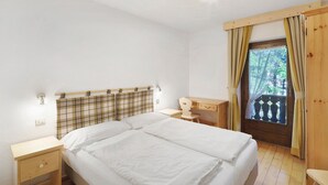 Une chambre à coucher avec un lit, un bureau, une chaise et une fenêtre avec des rideaux.