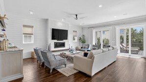 A spacious living room with a large TV, comfortable seating, and a sliding glass door to the outdoors.