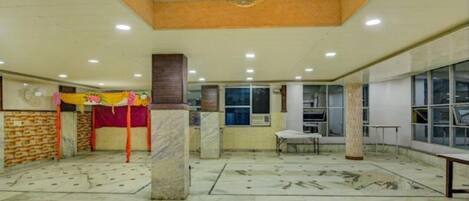 A spacious hall with a high ceiling, marble flooring, and a central pillar.