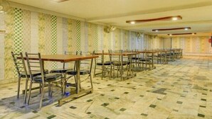 A large hall with rows of tables and chairs, patterned walls, and a tiled floor. - Hotel Shri Laxmi Palace (Kanpur)