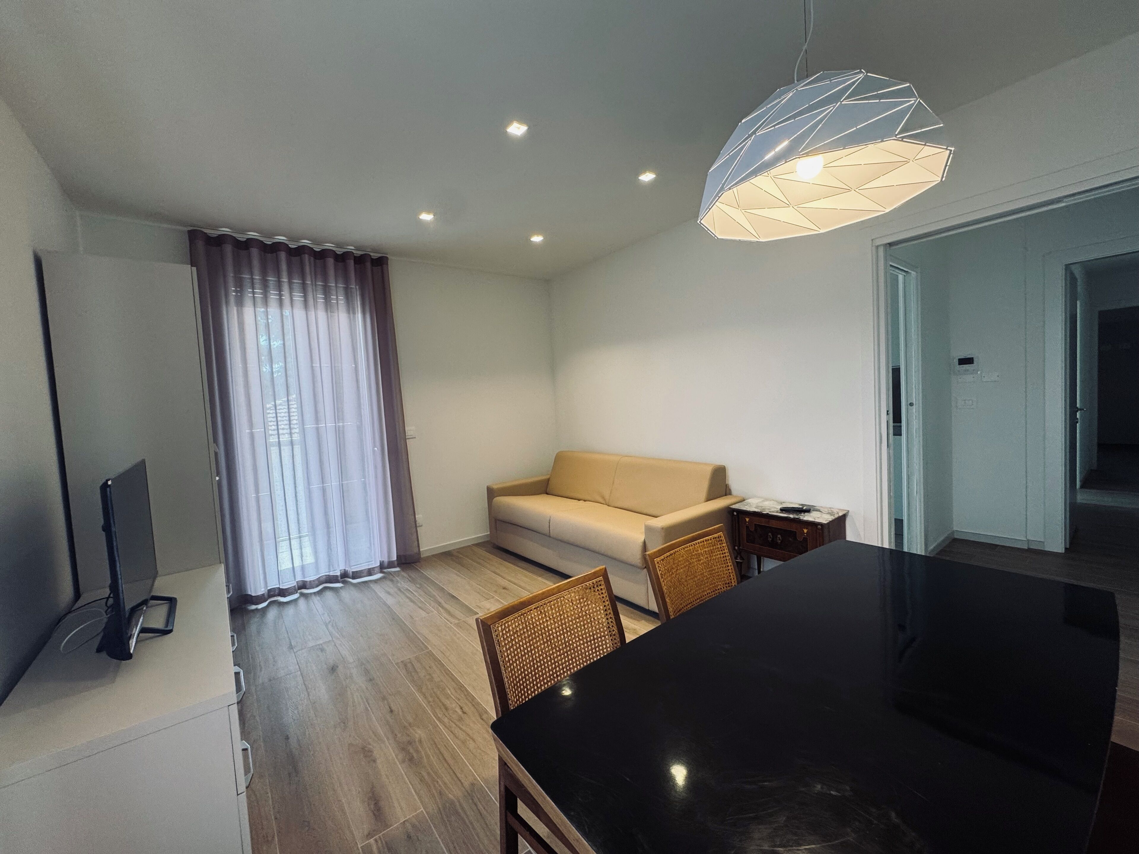 Una sala de estar moderna con sofá, mesa de comedor y televisor.