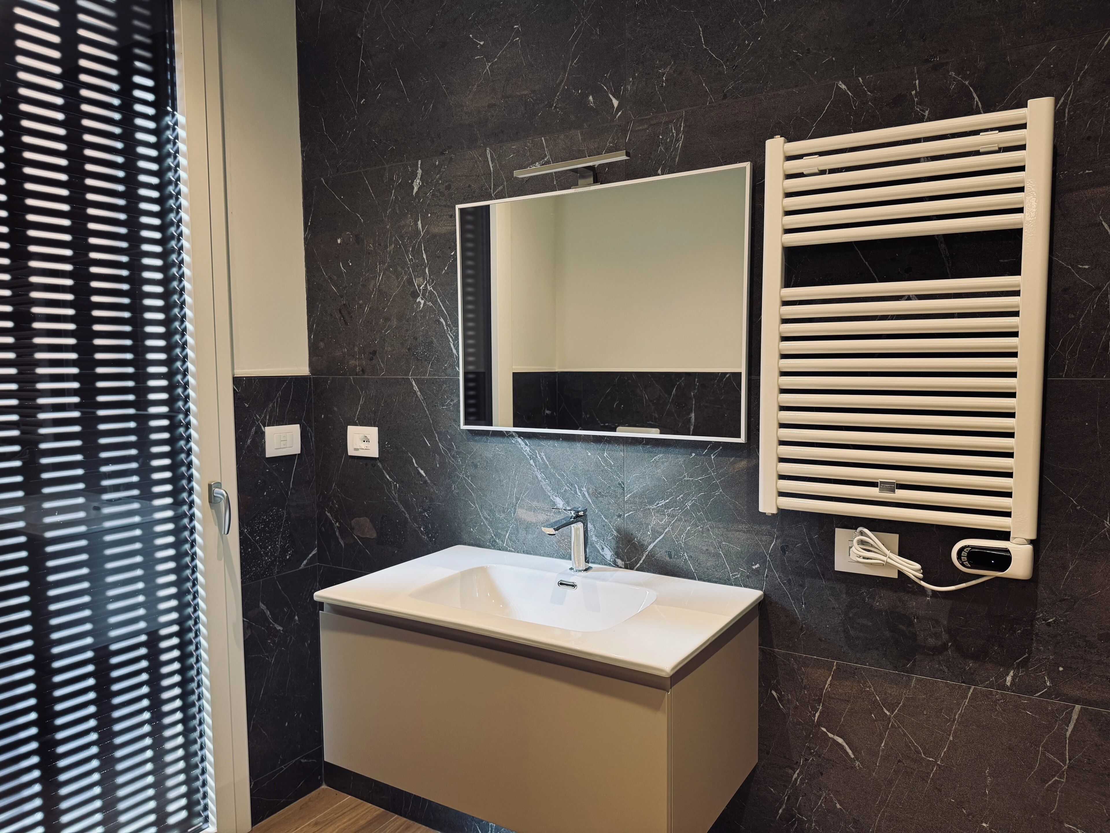 Une salle de bain moderne avec un lavabo blanc, un miroir et un porte-serviettes.