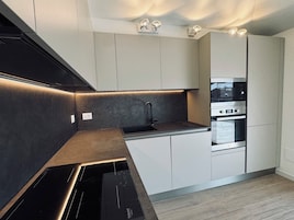 A modern kitchen with integrated appliances, a built-in oven, and a sleek countertop design.