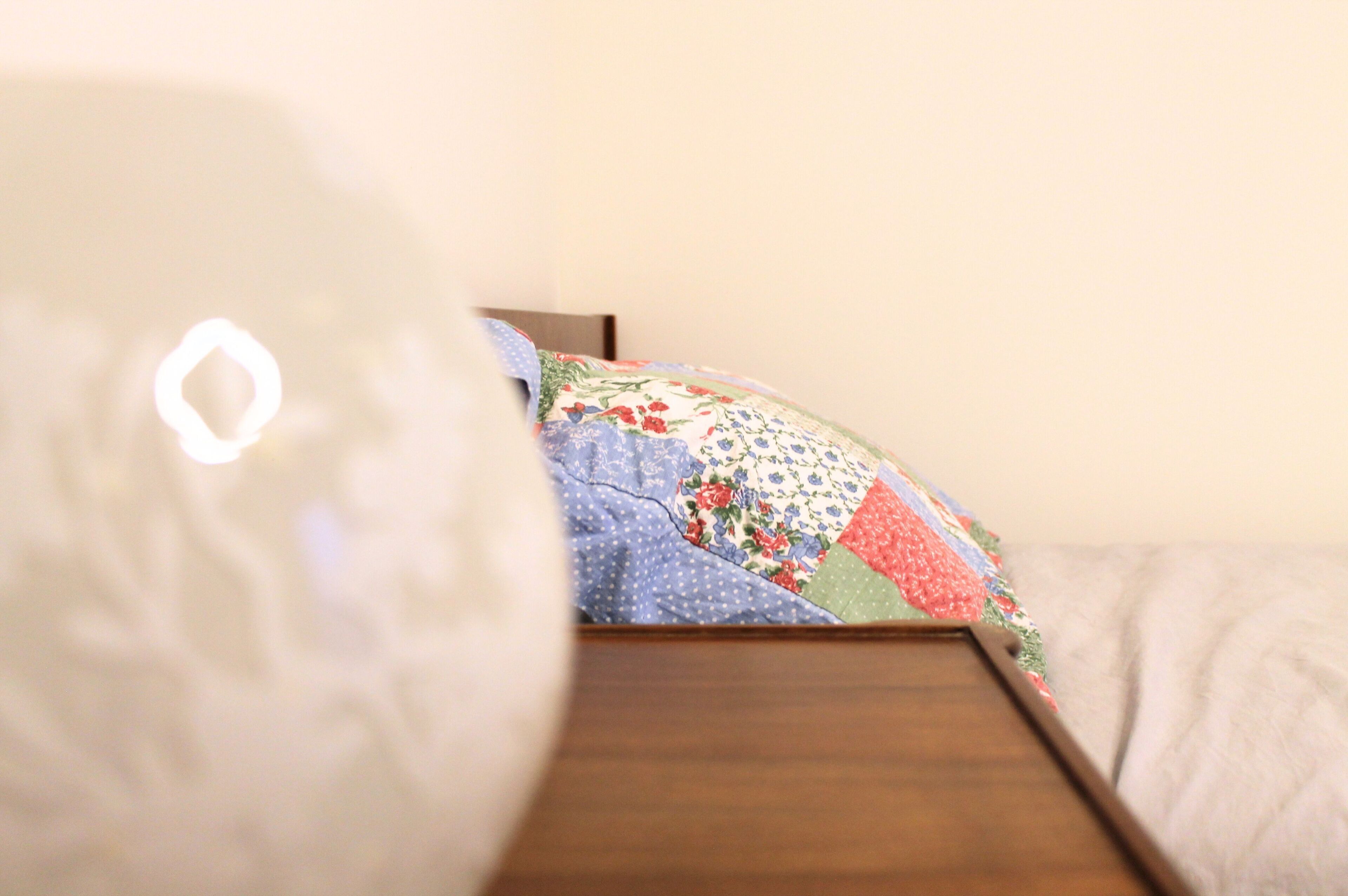 Uma cama com colcha colorida e cabeceira de madeira.