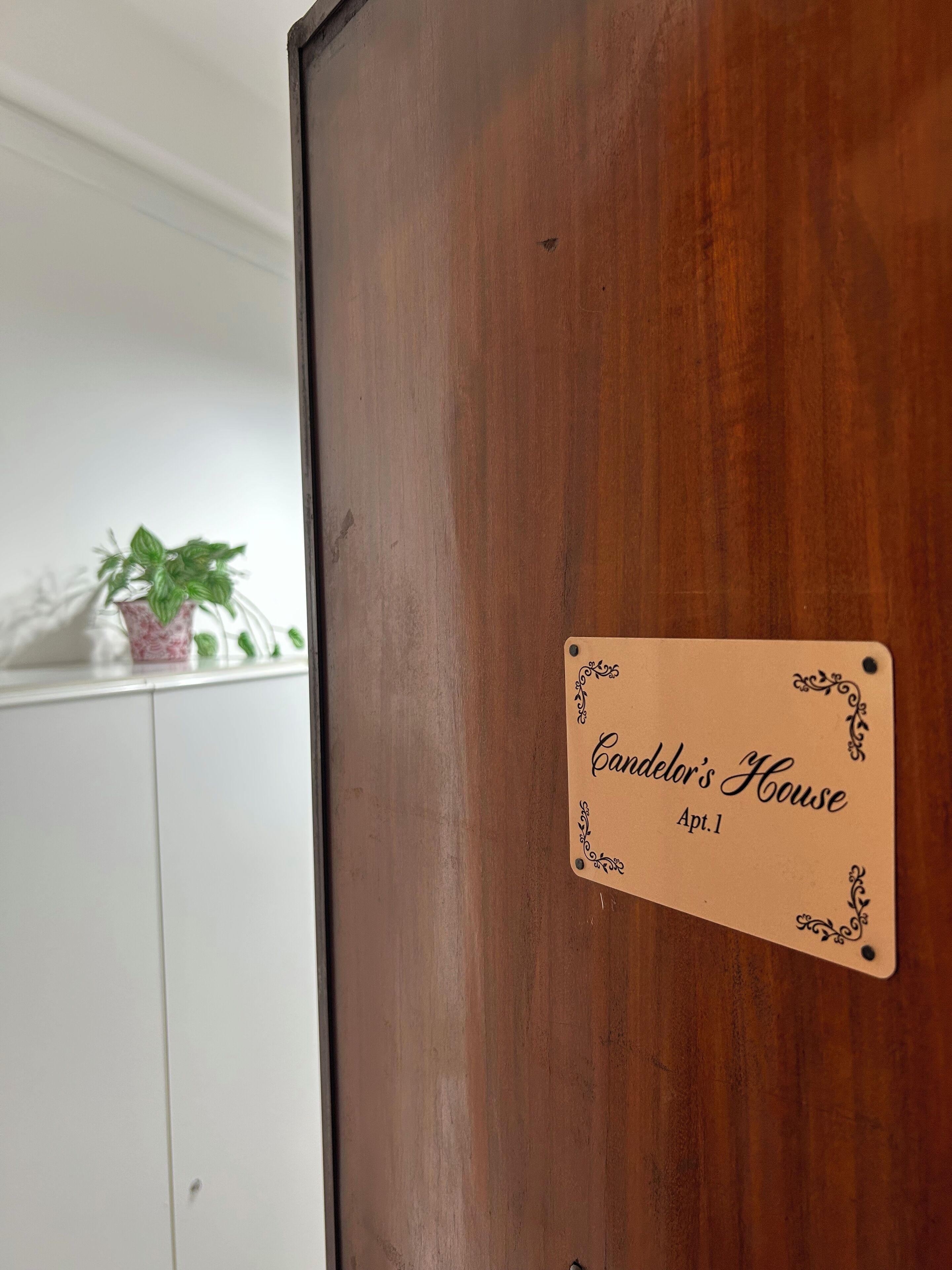 A wooden door with a plaque that reads "Candelor's House Apt. 1".